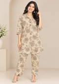 A woman models a two-piece beige and brown floral print kurta set in a neutral indoor setting with a beige archway background.
